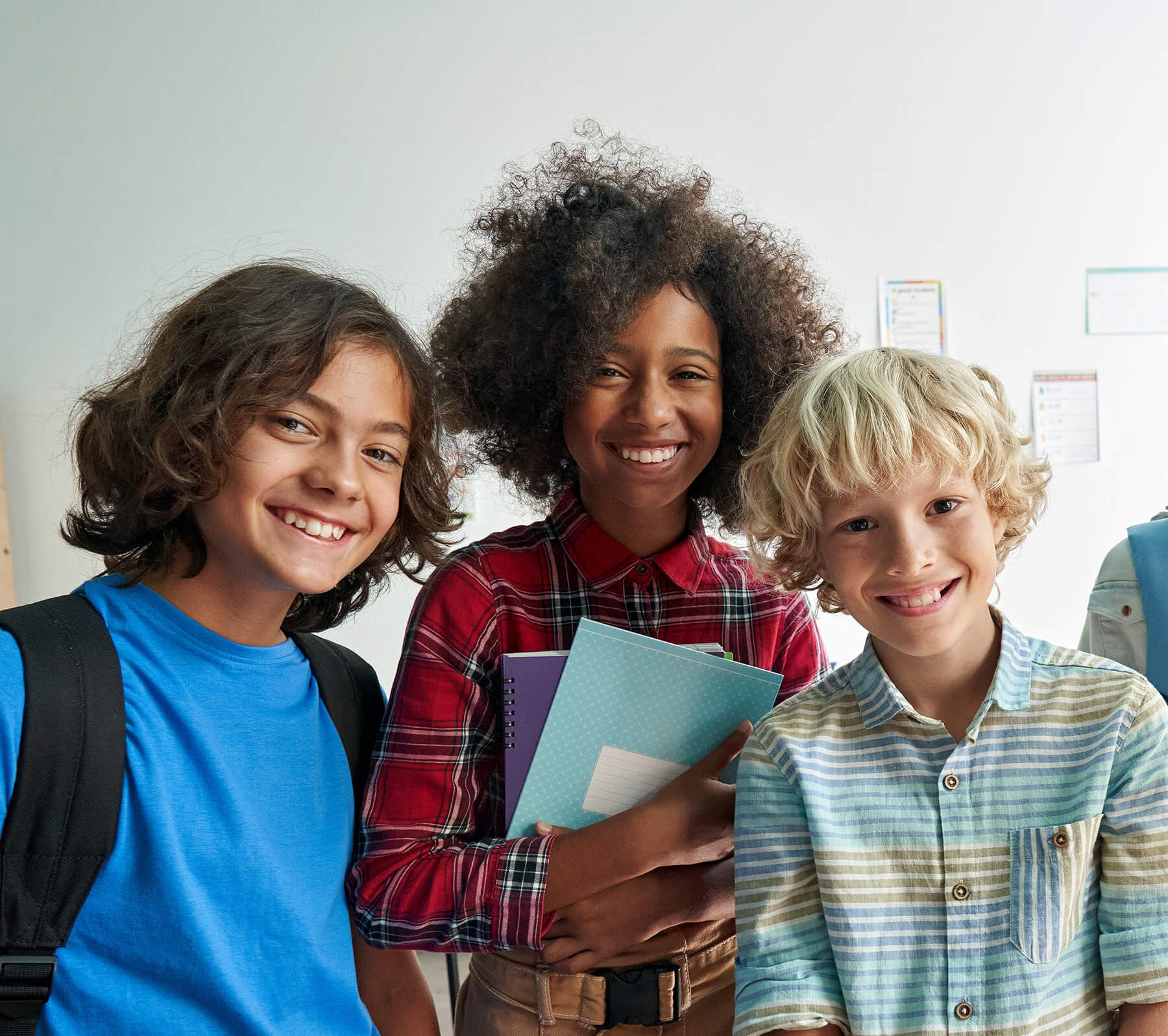 Happy diverse middle school students children group looking at camera standing in classroom. Smiling multiethnic tweens friends posing for group portrait together.