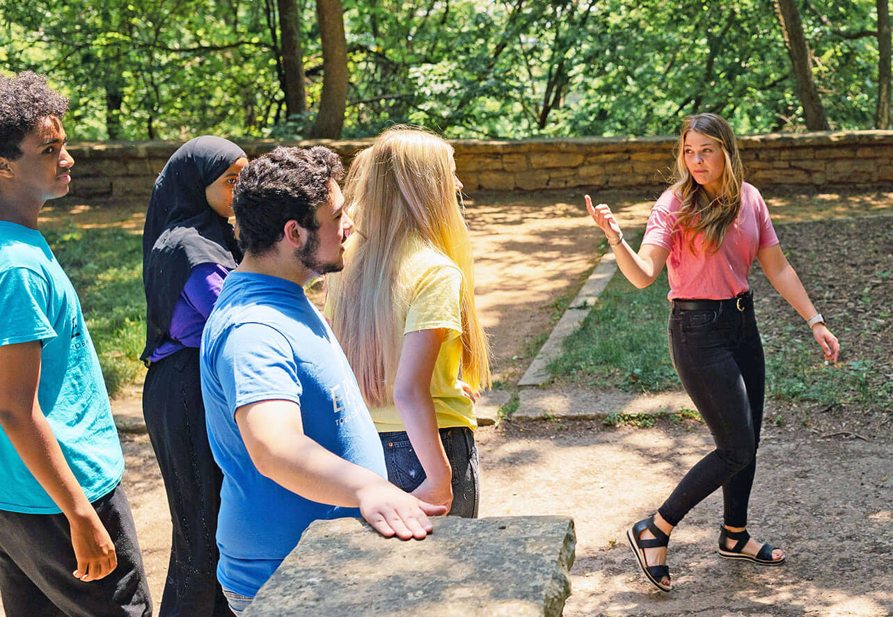 A group of students walk in the woods behind public health nurse Katie Austin.