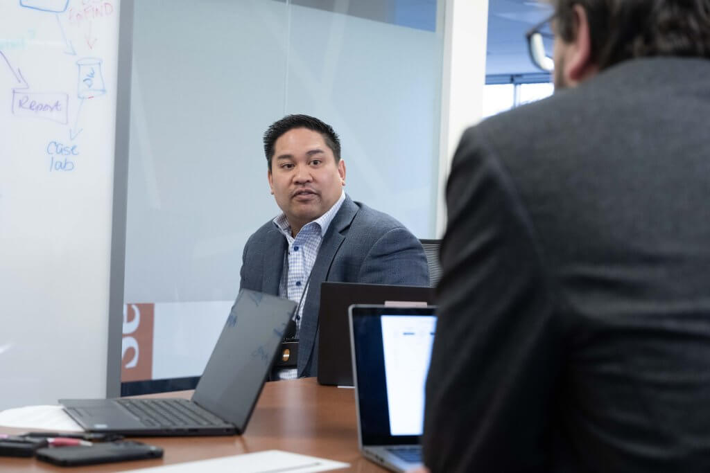 Noel Clarin sits in a conference room with colleagues